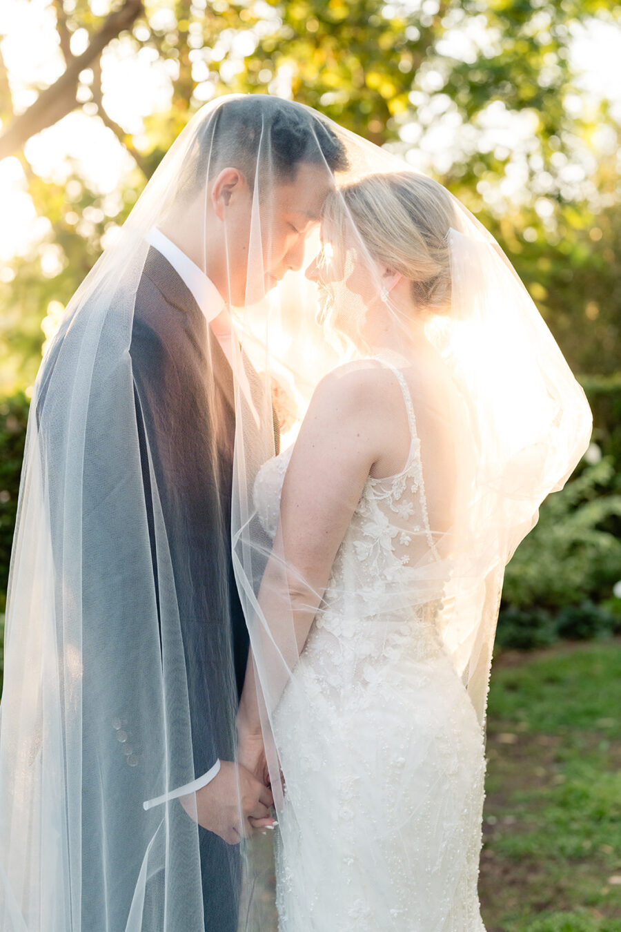 Bride and groom face to face under the bride's veil with the sun shining through during their wedding day at Rancho Bernardo Inn wedding venue in San Diego.