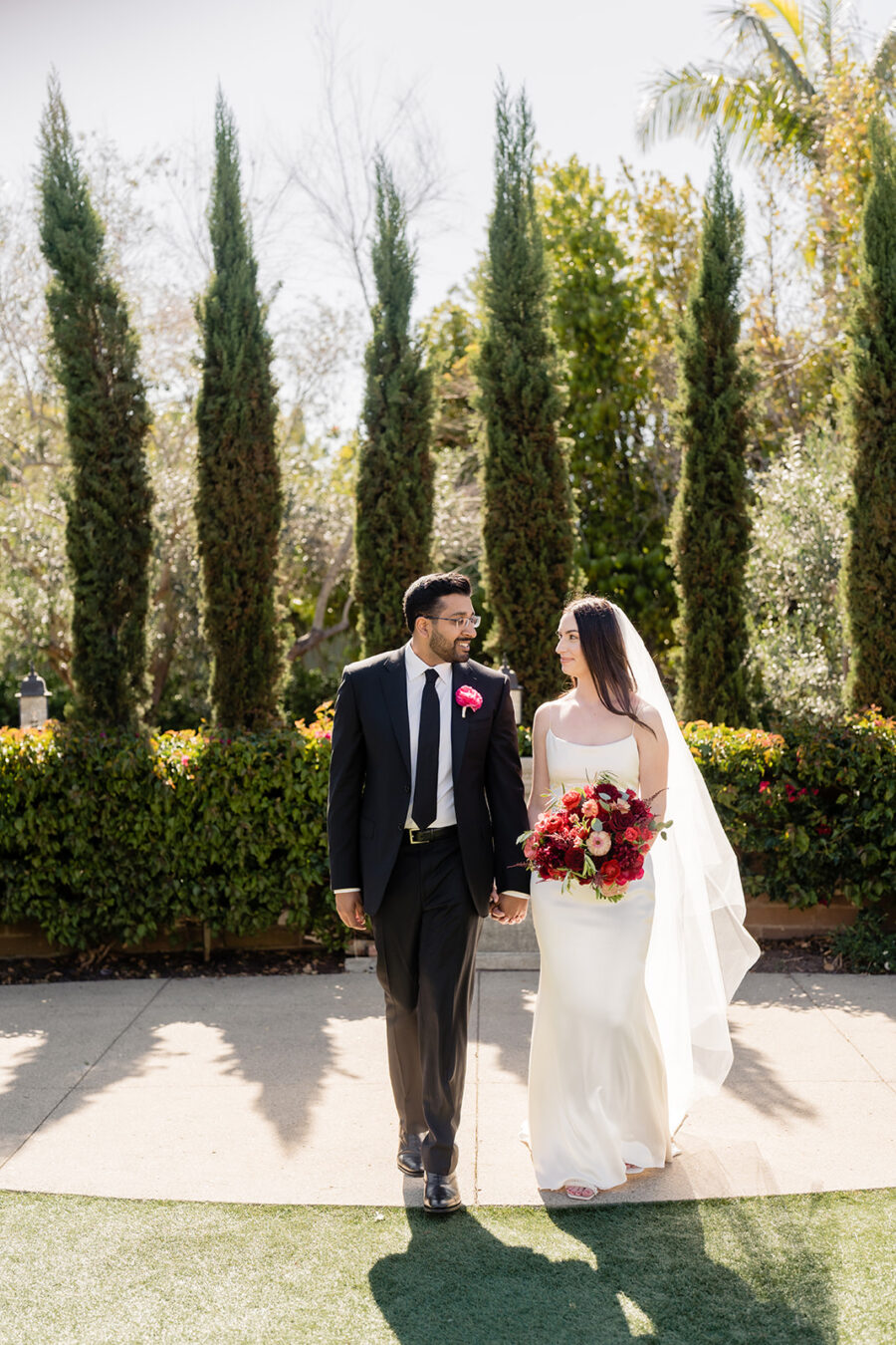 Bride and groom walking with the sun behind them on a lawn at Estancia La Jolla