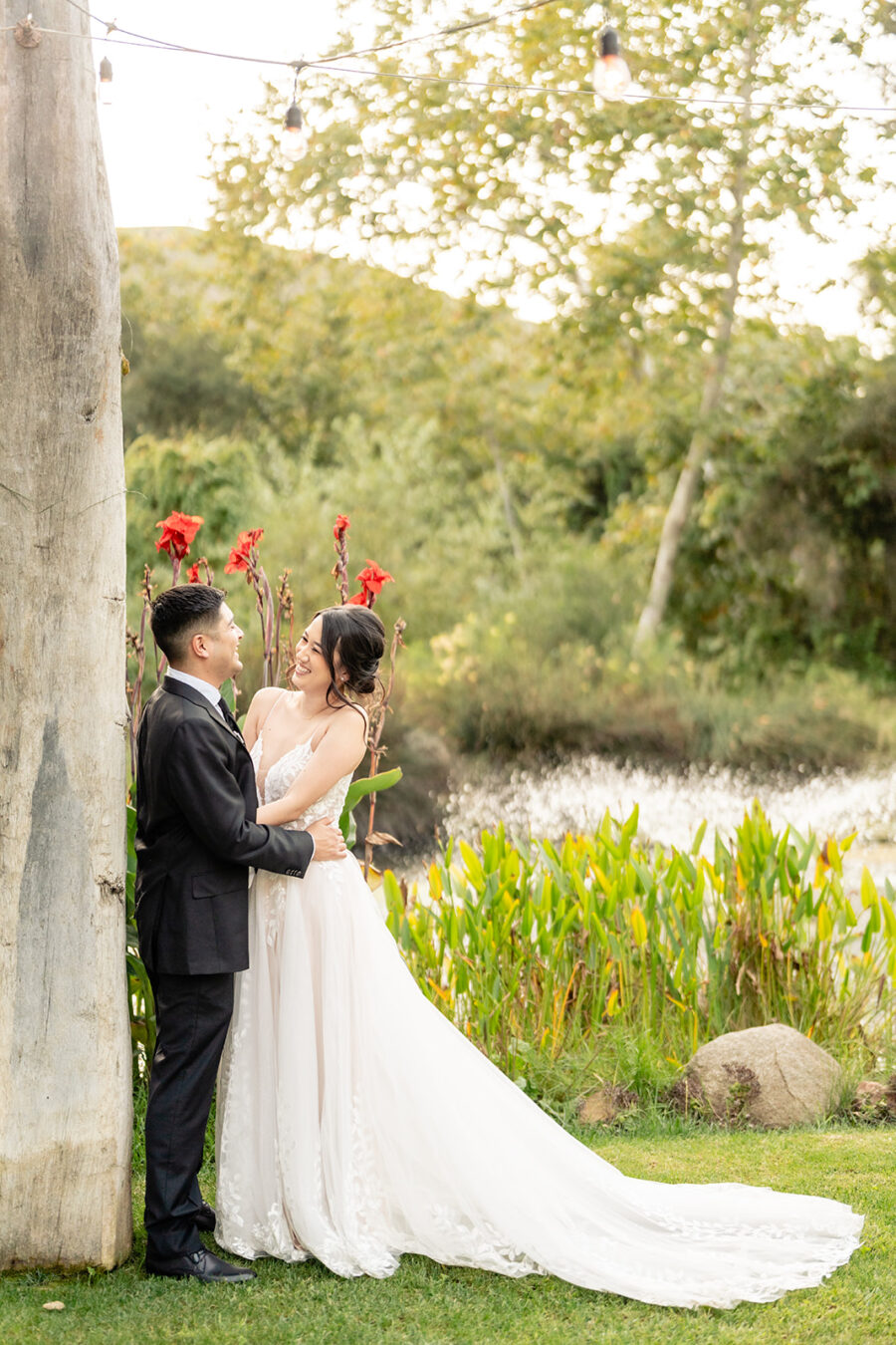 Bride and groom standing together in front of a pond 