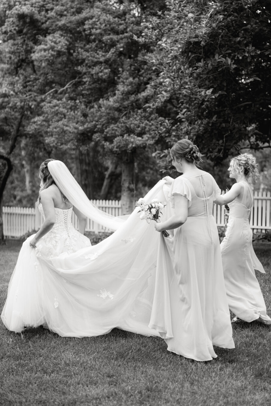 Bridesmaids holding the dress of a bride at Cedarmont Farms