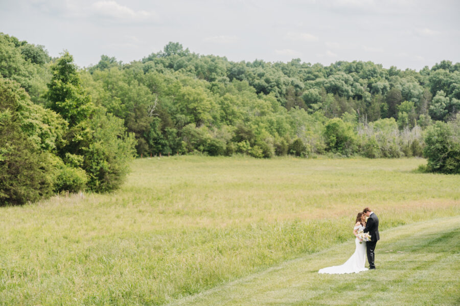 Bride and Groom standing in a field at their Spring Hill Wedding